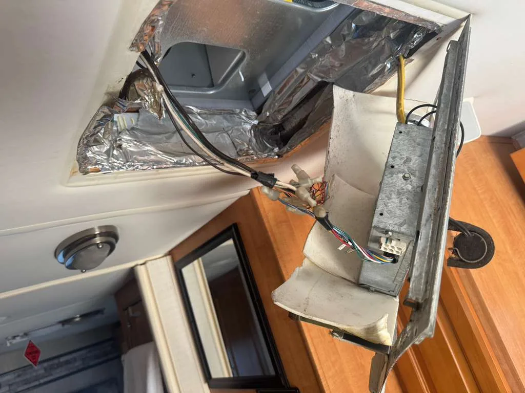 Ceiling vent assembly dropped out of an RV roof showing the ducting and foil insulation above the headliner