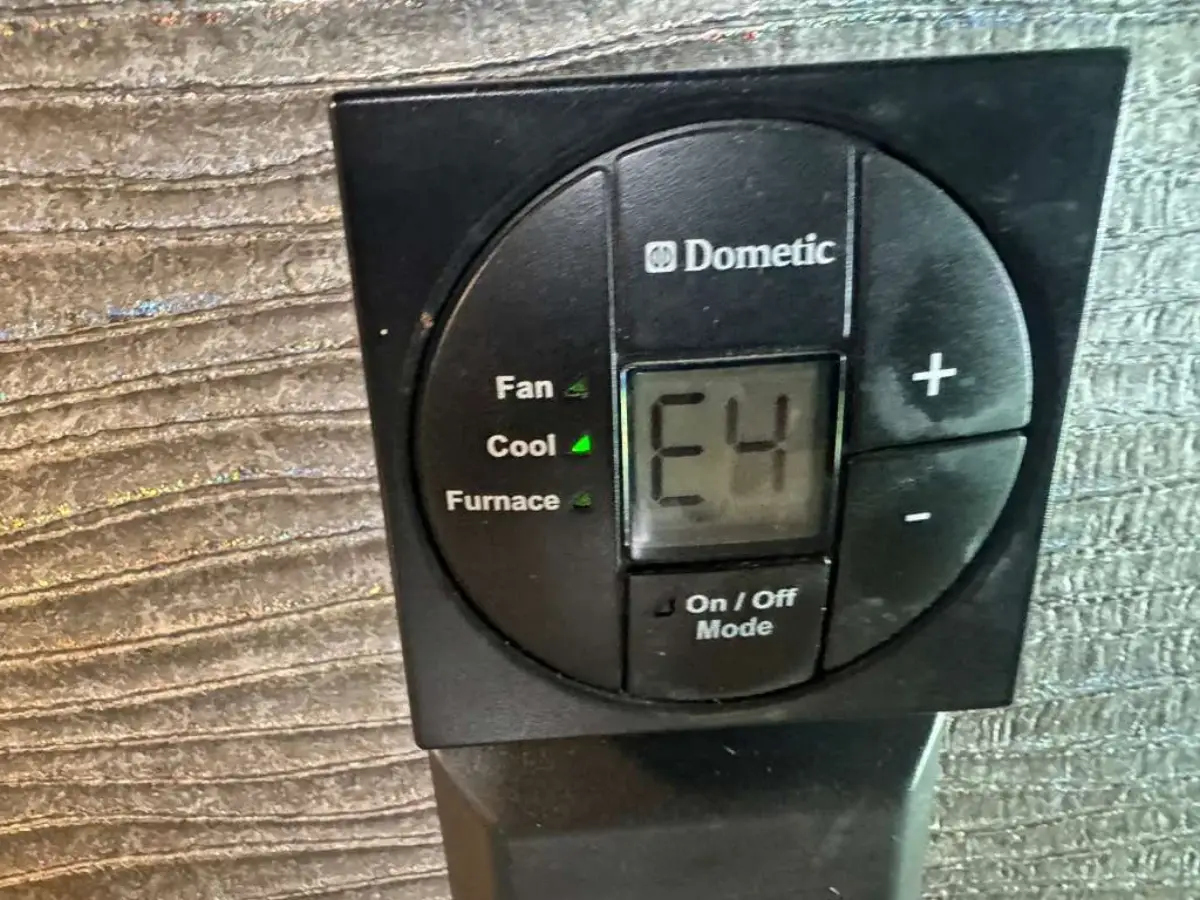 Dometic RV thermostat displaying an E4 fault code with the Fan, Cool and Furnace indicator lights visible